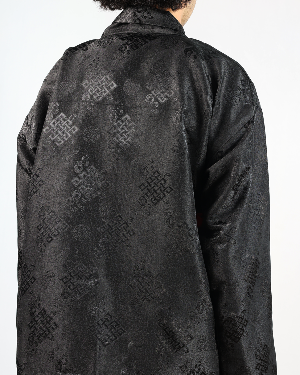 Back view of a stylish Wonju kimono shirt, showcasing intricate black fabric patterns and elegant design.